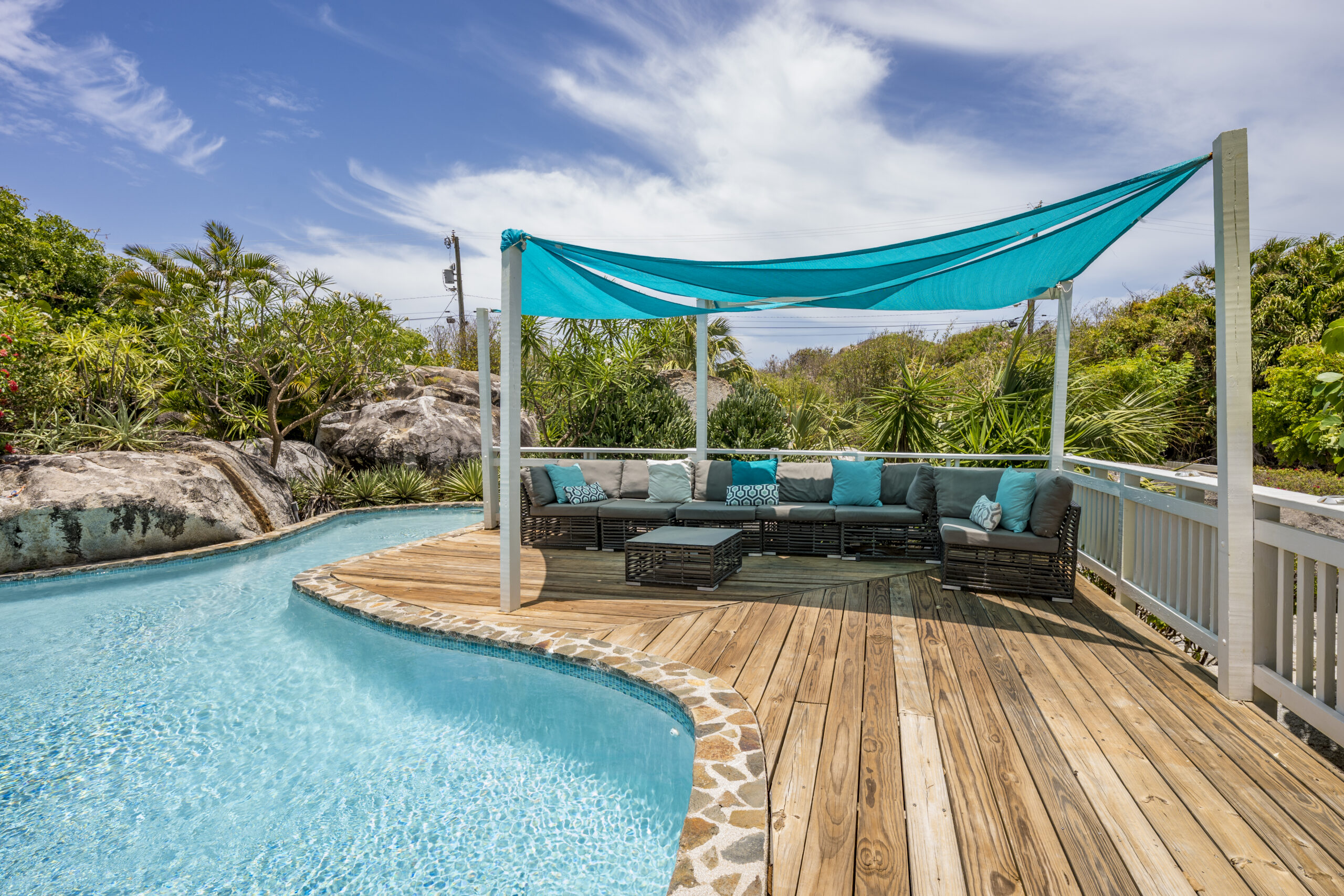Outdoor seating area by a pool with a blue canopy